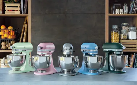 Cinq robots pâtissiers KitchenAid Classic ou Artisan de couleurs vives alignés sur un comptoir.