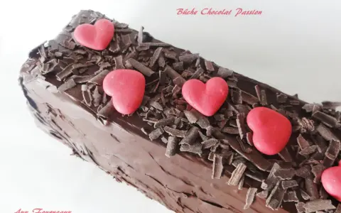 Bûche chocolat passion, un délice chocolaté orné de copeaux de chocolat et de cœurs rouges.