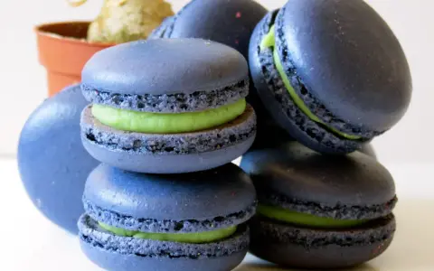 Macarons bleus avec une garniture verte vibrante, parfaits pour une recette macaron pistache.