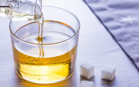Versez le sirop de glucose dans un bol. Une recette simple pour des desserts parfaits. Trois morceaux de sucre à côté.