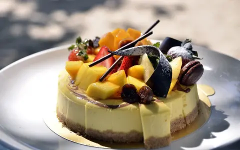 Gâteau crémeux sur un fond biscuit pour gâteau, garni de mangues, fraises, figues et chocolat.