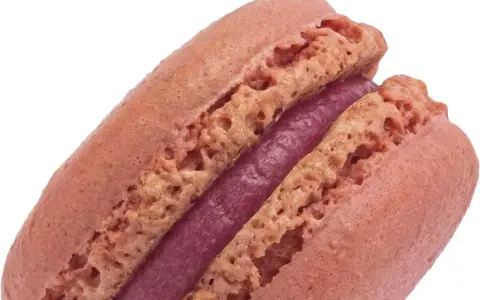 Un délicieux macaron framboise, avec sa coque rose pâle et sa ganache violette intense.