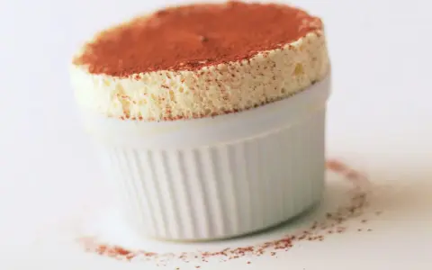 Un aérien soufflé au grand marnier, saupoudré de cacao, dans un ramequin blanc. Un délice léger et parfumé.