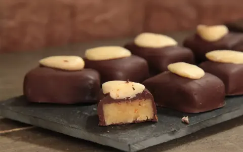 Délicieux bonbons au chocolat noir, garnis d'une pâte d'amande et surmontés d'une amande entière. Une recette gourmande à essayer !