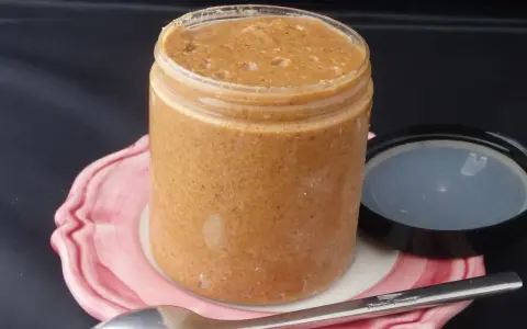 Un pot de praliné maison, onctueux et gourmand, prêt à être dégusté avec une cuillère.