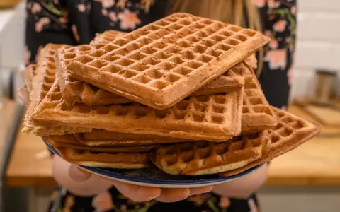 Une pile de gaufres dorées, prêtes à être dégustées. La pâte à gaufres a été cuite à la perfection, créant une texture croustillante à l'extérieur et moelleuse à l'intérieur.
