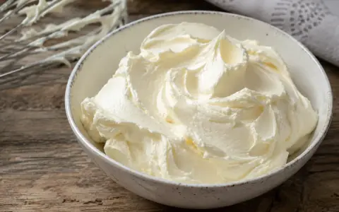 Un bol rempli de crème au beurre professionnelle, onctueuse et aérienne, prête à être utilisée pour des décorations pâtissières.