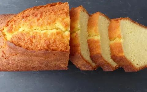 Un quatre-quarts breton, doré et moelleux, coupé en tranches sur fond sombre. Parfait pour une recette simple et gourmande.