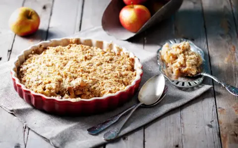 Un délicieux crumble aux pommes, avec sa pâte à crumble croustillante dorée, prêt à être dégusté.