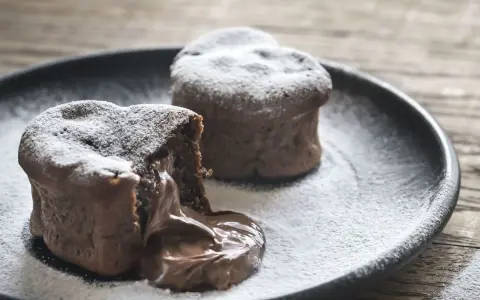 Deux coulants au chocolat inratables, saupoudrés de sucre glace, avec un cœur fondant qui déborde sur l'assiette.