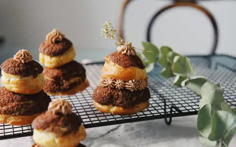 Délicieuses religieuses au chocolat, empilées sur une grille, ornées de crème et d'une touche de verdure.