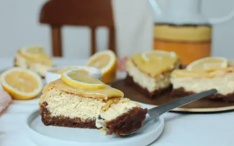 Tranches de cheesecake citron, garnies de rondelles de citron frais, sur une assiette blanche.