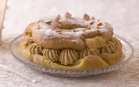 Un Paris-Brest rond, saupoudré de sucre glace et d'amandes effilées, garni d'une généreuse crème diplomate.