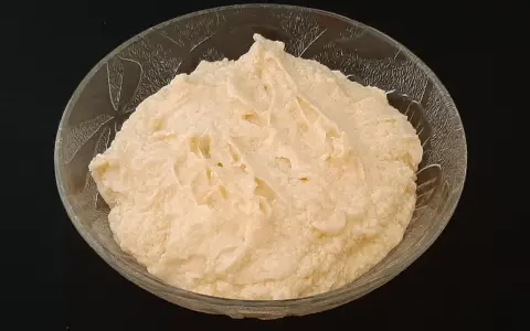 Crème d'amande onctueuse dans un bol en verre texturé, prête à être dégustée.