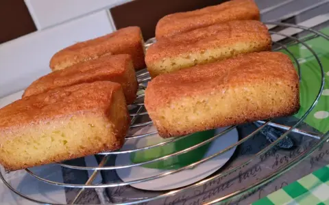 Six financiers dorés, des quatre quarts sans œuf, refroidissent sur une grille.