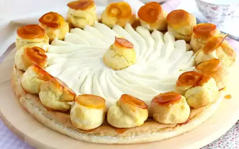Un magnifique gâteau Saint-Honoré, orné de choux caramélisés et d'une crème onctueuse, prêt à être dégusté.