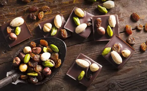 Carrés de chocolat noir Callebaut garnis d'amandes, noisettes, pistaches et raisins secs. Un délice à déguster !
