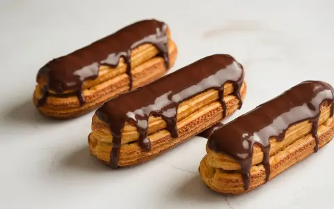 Trois éclairs au chocolat, parfaits pour une recette opera. La ganache dégouline sur la pâte à choux dorée.