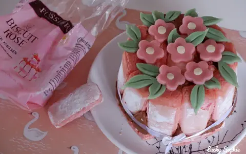 Charlotte aux biscuits roses de Reims, décorée de fleurs en pâte d'amande. Un biscuit rose saupoudré de sucre est à côté.