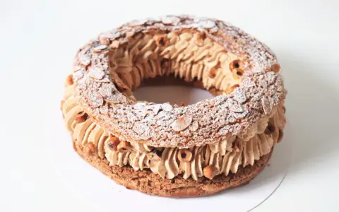 Un Paris Brest meilleur du chef, généreusement garni de crème pralinée et parsemé d'amandes effilées et de noisettes.