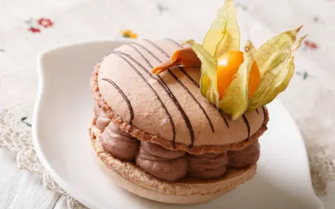 Un délicieux macaron chocolat au lait, garni de crème onctueuse et décoré d'une physalis orangée.