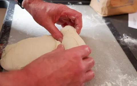 Mains travaillant la pâte à pain, étape d'autolyse. La pâte est souple et prête à être façonnée.