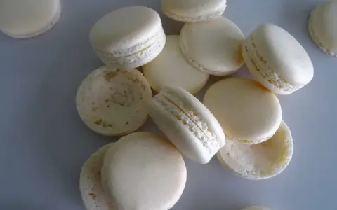 Des macarons blancs, certains assemblés, d'autres séparés, prêts pour la cuisson macaron chaleur tournante.