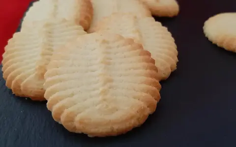 Un délicieux biscuit amande aux motifs striés, posé sur une surface sombre. Parfait pour accompagner un café.