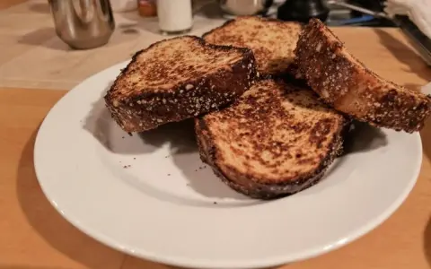 Quatre tranches de pain dur au four, dorées et croustillantes, sur une assiette blanche.