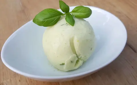 Une boule de sorbet citron vert et basilic, parfaite pour une recette sorbet citron professionnel. Délicatement garnie de feuilles de basilic frais.