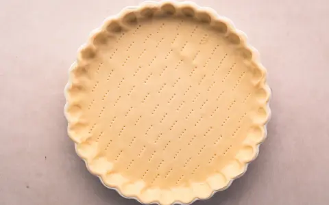 Pâte brisée salée prête à être garnie. Les petits trous préparent la base pour une cuisson parfaite.