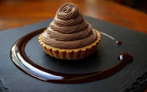 Délicieux Mont Blanc au chocolat, une recette gourmande à essayer. La crème onctueuse forme un cône parfait sur la tartelette.