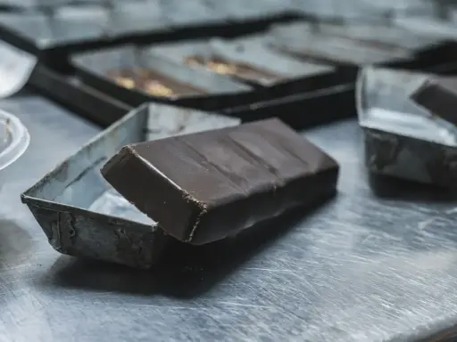 Une tablette de chocolat posée sur une petite boîte métallique. Idéal pour apprendre comment faire des copeaux de chocolat.