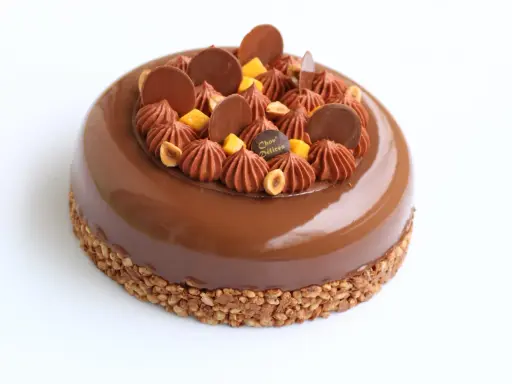 Entremet au chocolat avec un biscuit croustillant pour entremet, garni de rochers chocolatés, noisettes et dés de mangue.
