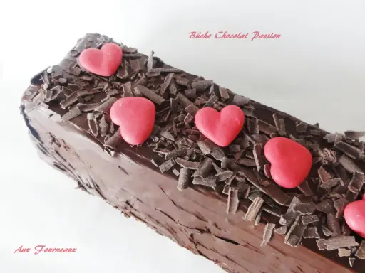 Bûche chocolat passion, un délice chocolaté orné de copeaux de chocolat et de cœurs rouges.