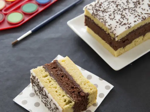 Une tranche de gâteau napolitain, digne du meilleur pâtissier, avec une palette de peinture et un pinceau.