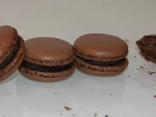 Trois macarons au chocolat et un croqué, parfaits pour une recette macaron chocolat.