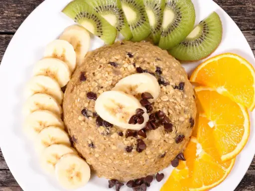 Un délicieux bowl cake flocon d'avoine garni de rondelles de banane, de tranches de kiwi et d'orange, parsemé de pépites de chocolat.