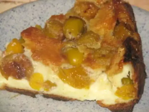 Une part de flan aux mirabelles, avec sa croûte dorée et sa garniture crémeuse aux fruits jaunes.