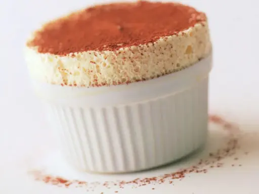 Un aérien soufflé au grand marnier, saupoudré de cacao, dans un ramequin blanc. Un délice léger et parfumé.