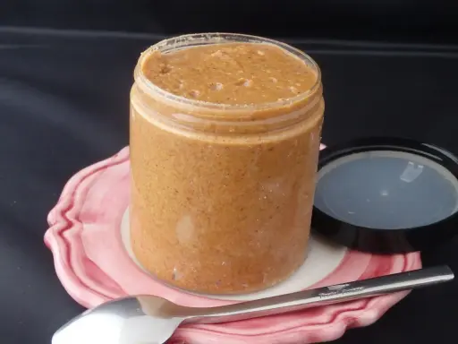 Un pot de praliné maison, onctueux et gourmand, prêt à être dégusté avec une cuillère.
