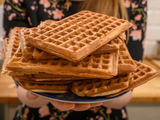 Une pile de gaufres dorées, prêtes à être dégustées. La pâte à gaufres a été cuite à la perfection, créant une texture croustillante à l'extérieur et moelleuse à l'intérieur.