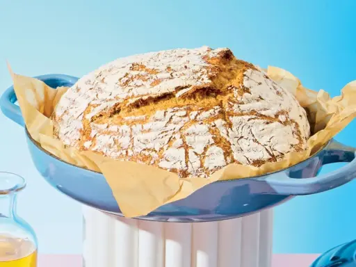 Pain maison doré dans une cocotte bleue, prêt à être dégusté. Le temps de cuisson pain 500g est parfait pour cette croûte craquelée.
