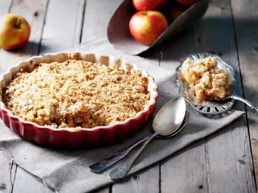 Un délicieux crumble aux pommes, avec sa pâte à crumble croustillante dorée, prêt à être dégusté.