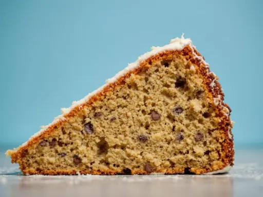 Tranche de gâteau au froment, parsemée de pépites de chocolat, avec un glaçage blanc. Un délice !
