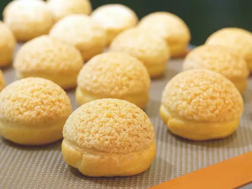 Une rangée de craquelins choux dorés et croustillants, prêts à être dégustés.