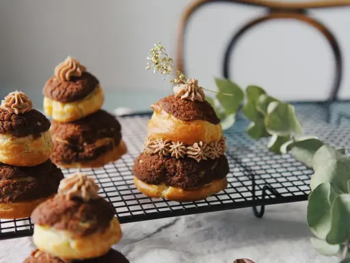 Délicieuses religieuses au chocolat, empilées sur une grille, ornées de crème et d'une touche de verdure.