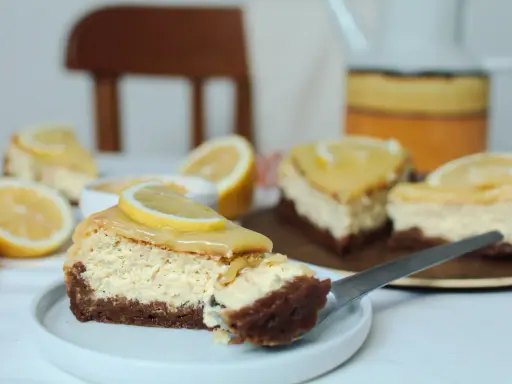 Tranches de cheesecake citron, garnies de rondelles de citron frais, sur une assiette blanche.