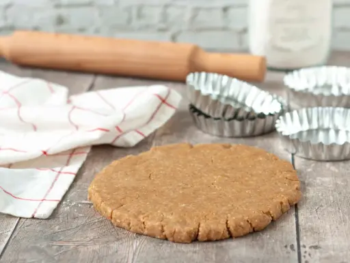 Pâte sablée prête pour la cuisson au four à chaleur tournante. Rouleau à pâtisserie, moules et torchon à proximité.