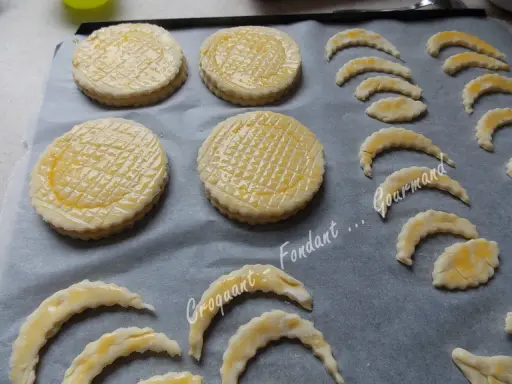 Sur une plaque, des disques de pâte feuilletée prêts à cuire, certains en forme de croissant, pour une délicieuse croute vol au vent.
